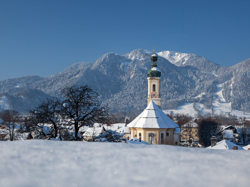 Ortsmitte Lenggries mit Pfarrkirche Sankt Jakob und Brauneck im Winter