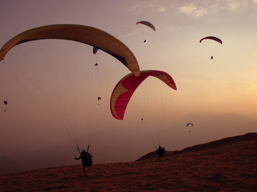 Gleitschirmflieger beim Start am Brauneck bei Sonnenuntergang