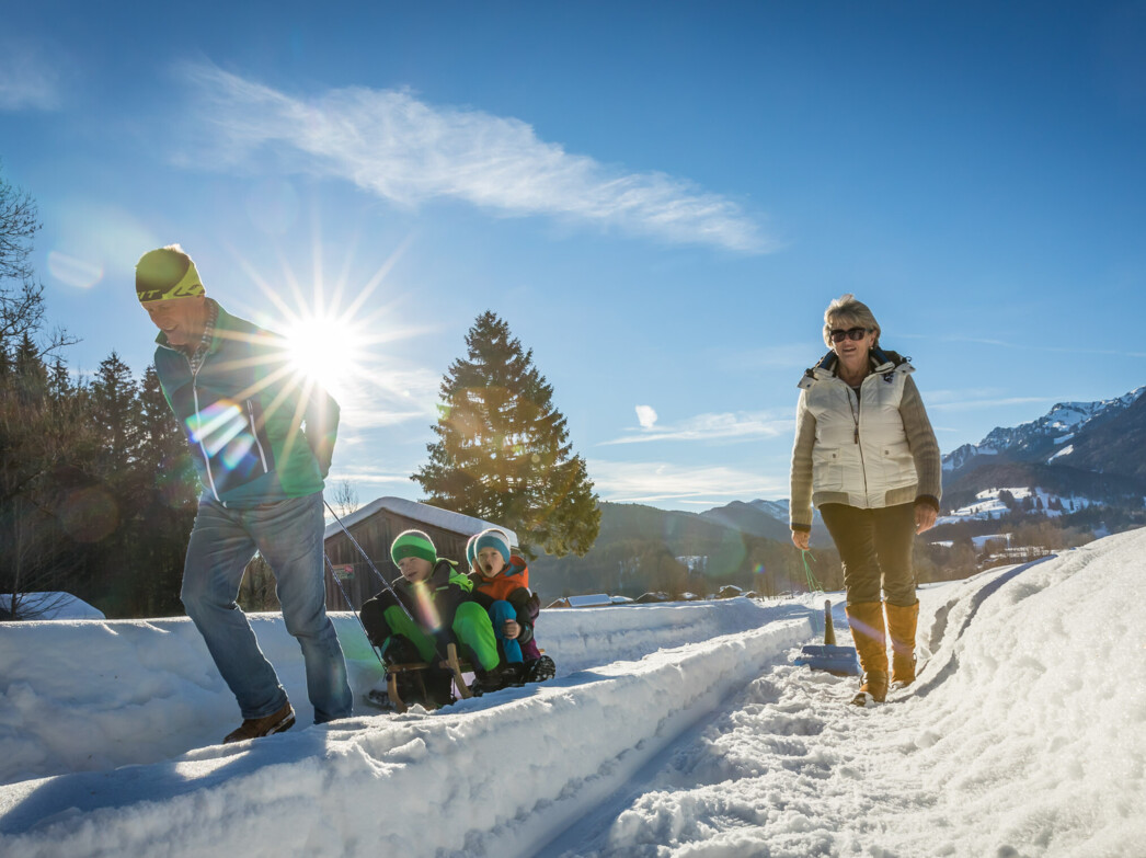 Familie beim Winterwandern mit Schlitten