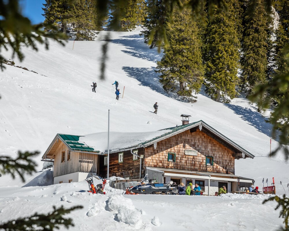 Blick auf die Quengeralm im Winter mit Skitourengehern im Hintergrund