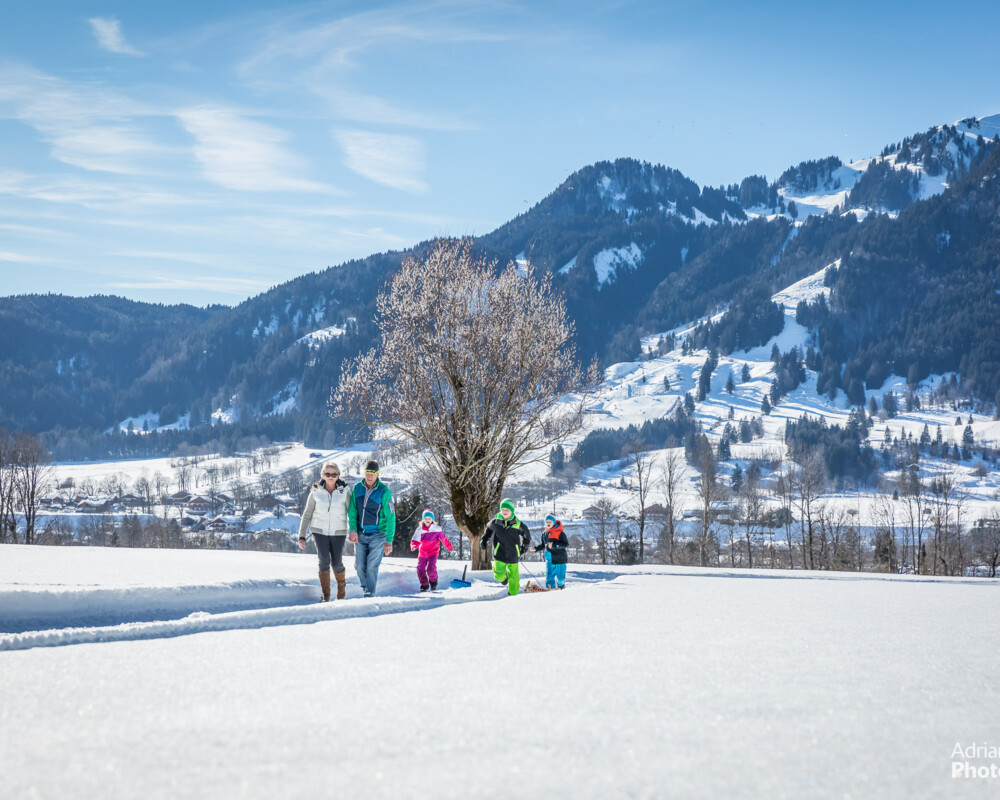 Familie beim Winterwandern mit Lenggries und Brauneck im Hintergrund