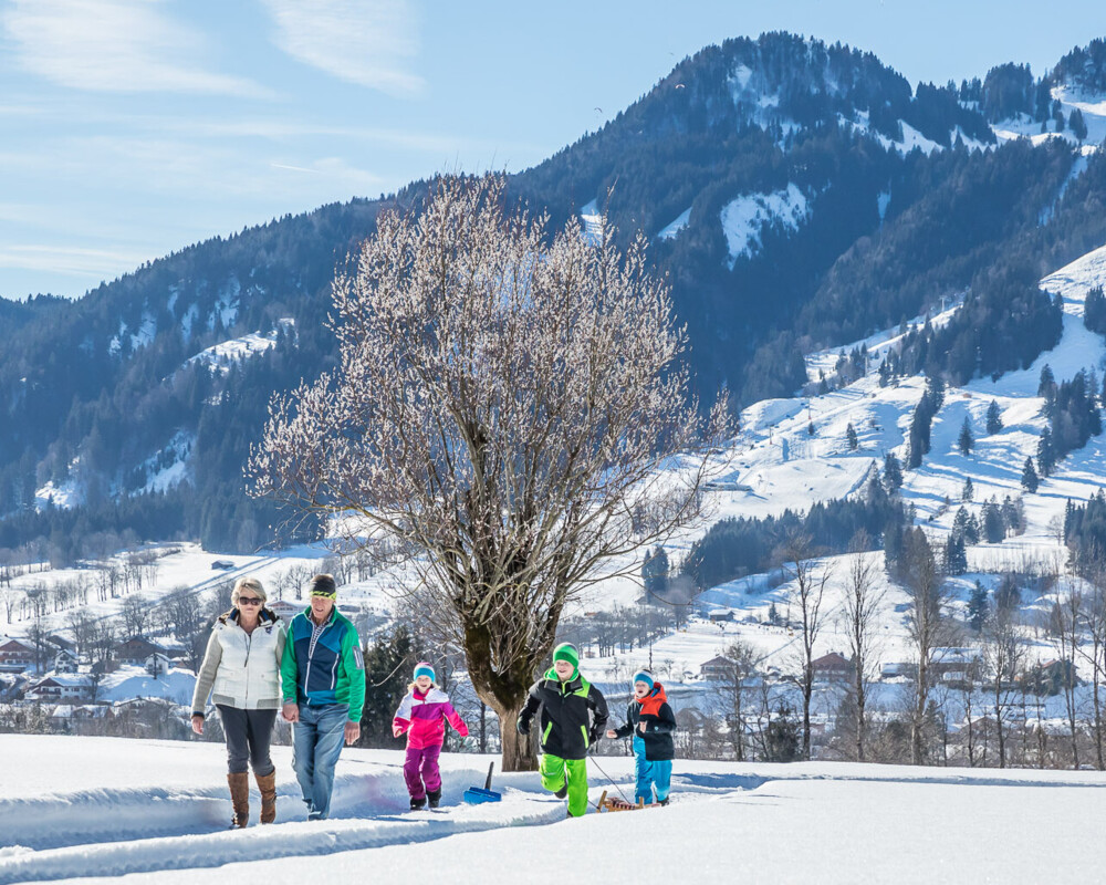 Familie beim Winterwandern mit Lenggries und Brauneck im Hintergrund