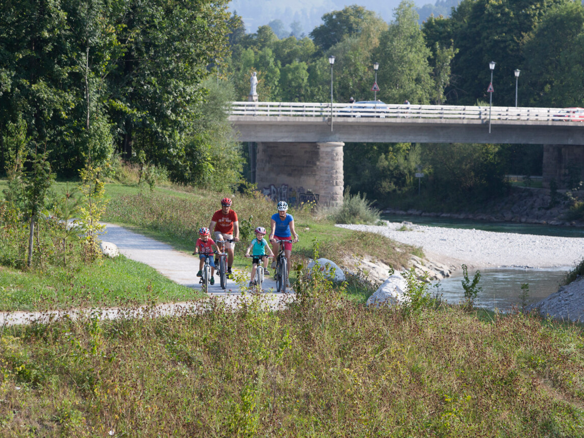 Familie auf dem Isarradweg mit Isarbrücke im Hintergrund