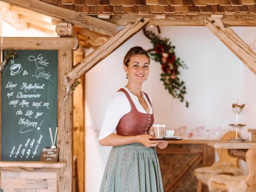 Eine Frau mit Cafetasse und Tablet beim Bedienen