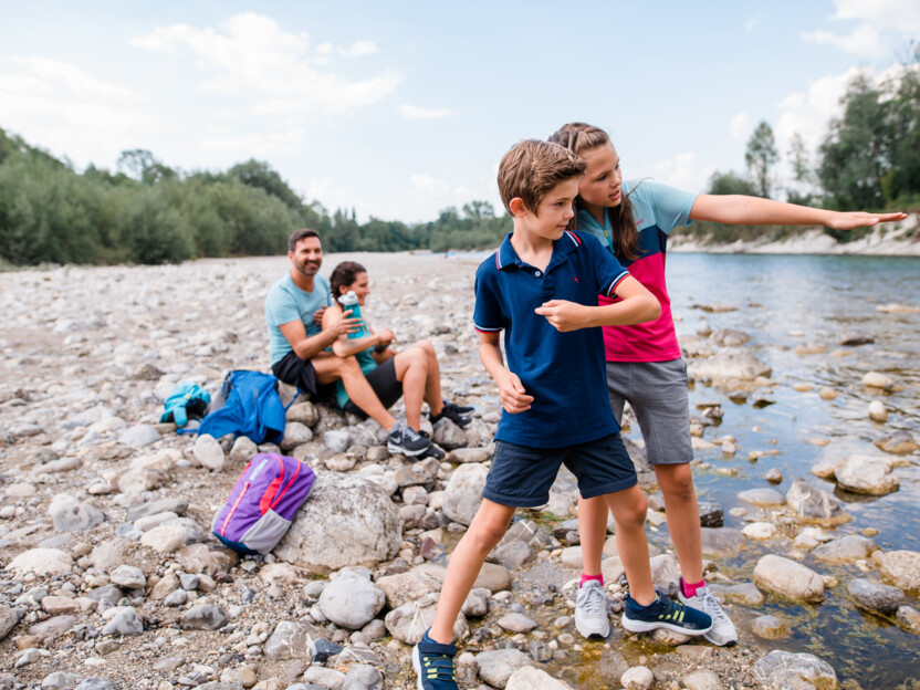 Familie lässt Steine über die Isar in Lenggries hüpfen