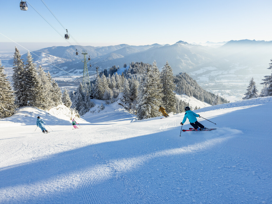 Skifahren am Brauneck: Talabfahrt mit Blick auf verschneite Gipfel.