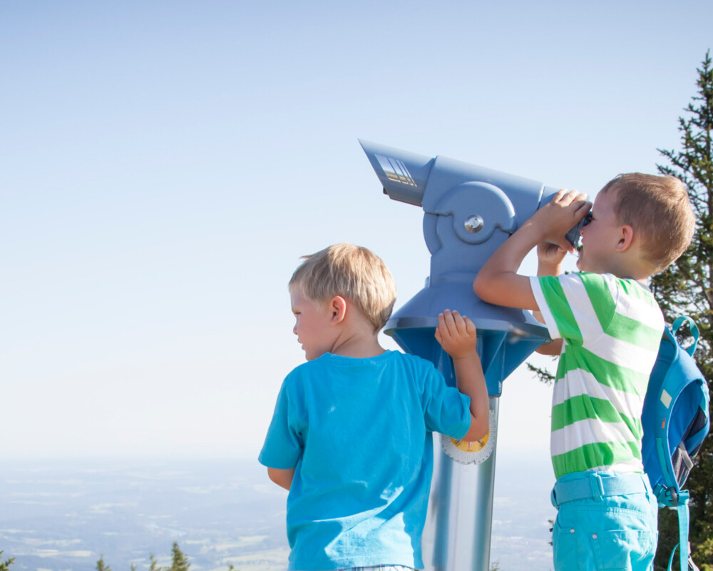 Zwei kleine Jungs blicken durch das Fernrohr am Brauneck und genießen den Ausblick