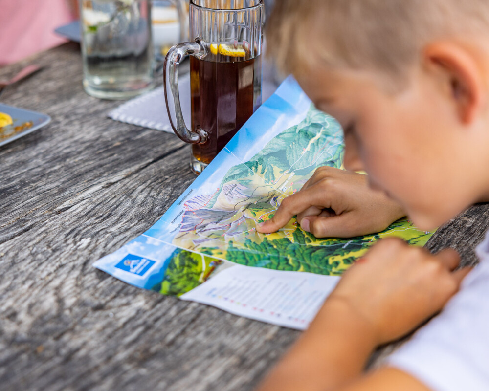 Ein Junge schaut auf die Panorama Wanderkarte beim Essen