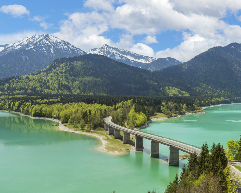 Sylvensteinsee mit Brücke und verschneitem Karwendelgebirge im Hintergrund