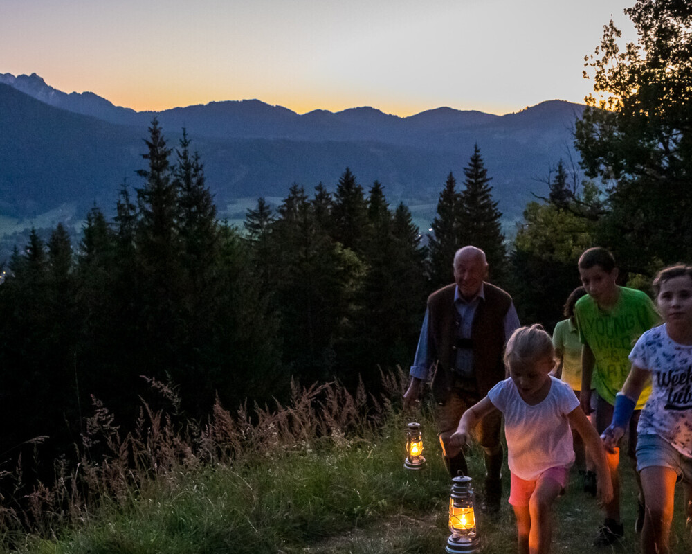 Kinder mit Laternen bei Sonnenuntergang am Berg