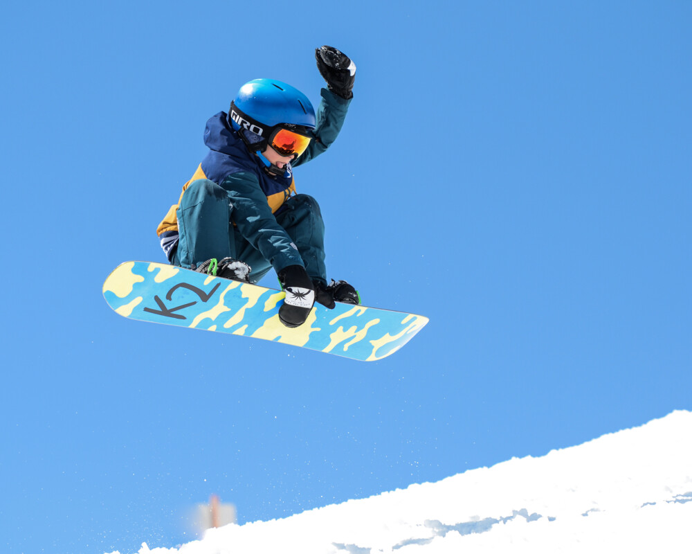 Kind beim Sprung mit dem Snowboard