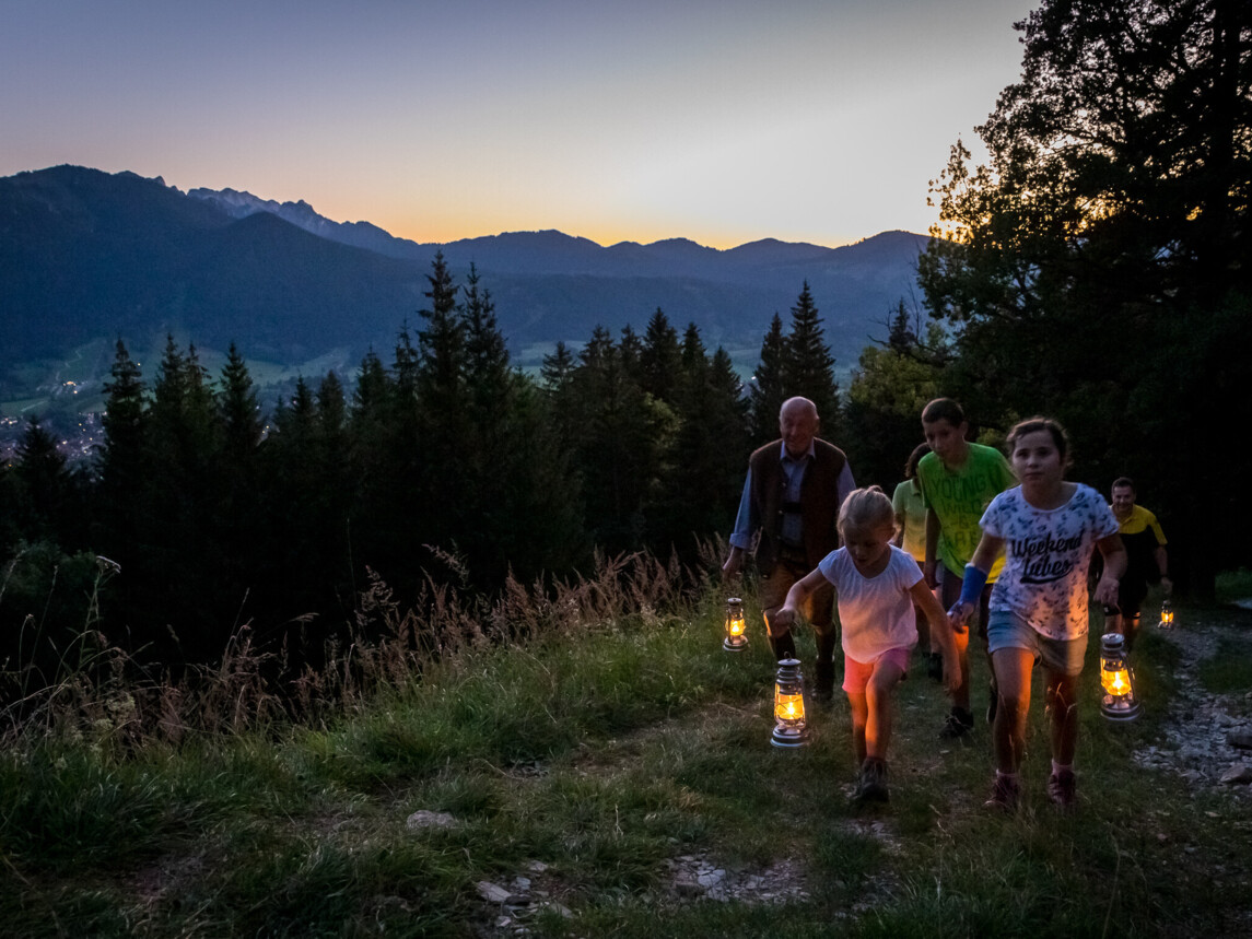 Kinder mit Laternen bei Sonnenuntergang am Berg
