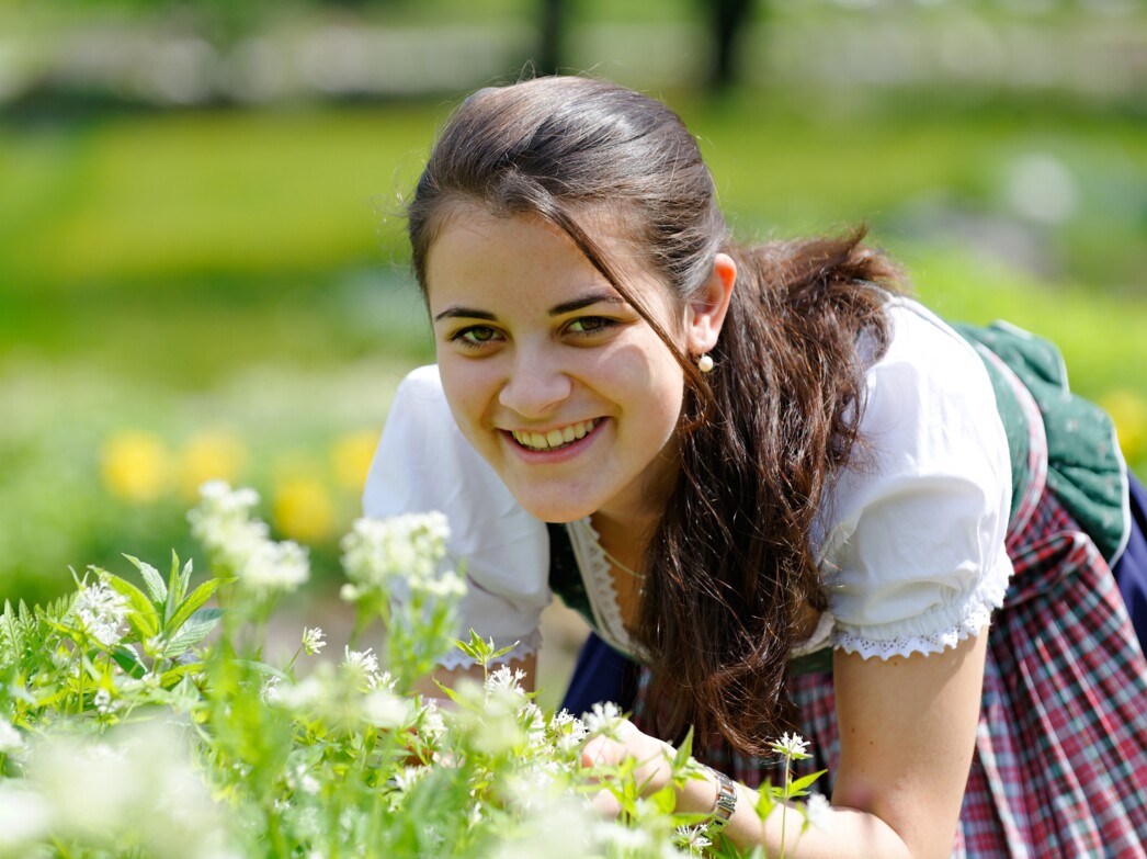 Eine Frau duftet an Blumen im Kräutergarten