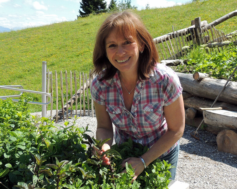 Eine Frau im Kräutergarten auf der Stie Alm