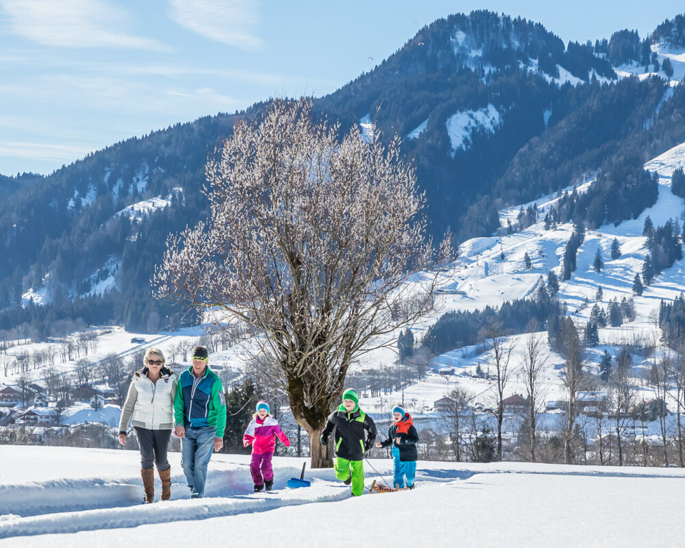 Familie beim Winterwandern mit Lenggries und Brauneck im Hintergrund