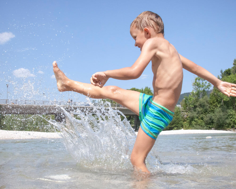 Junge spritzt Wasser in der Isar