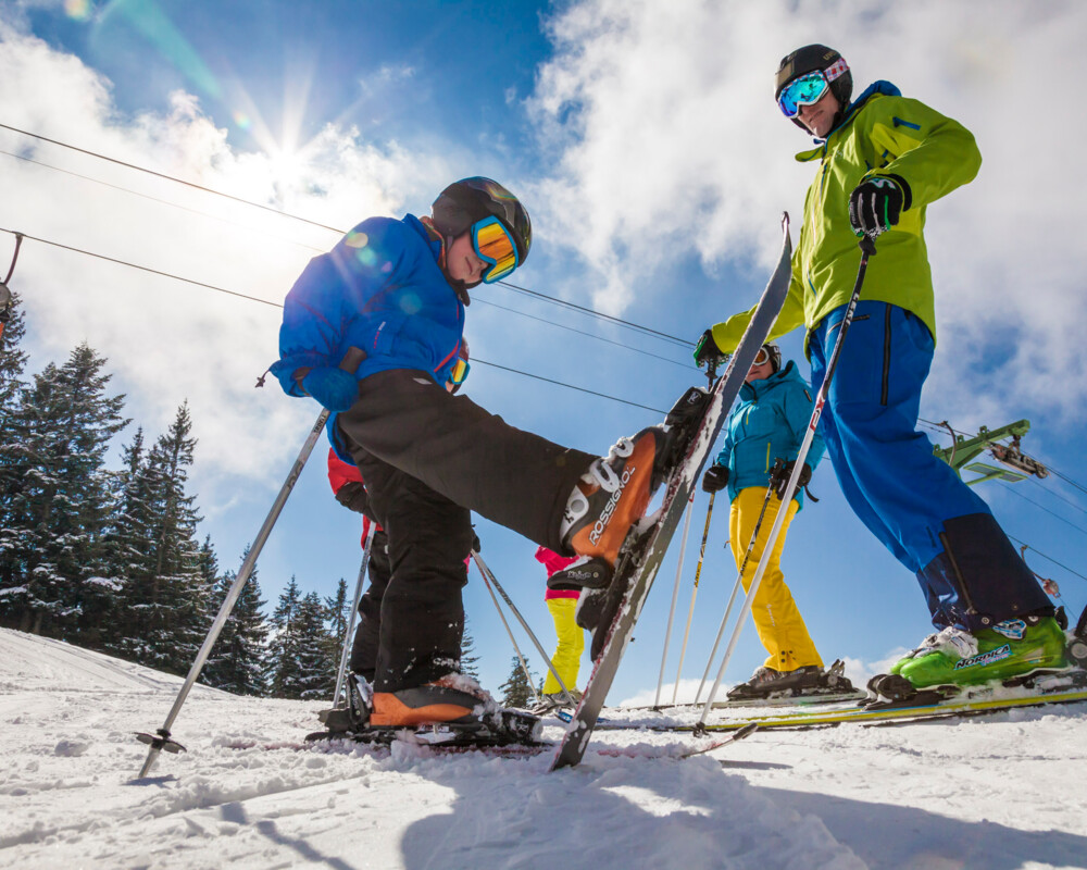 ein Junge stekt seinen Ski senkrecht in den Boden hinein