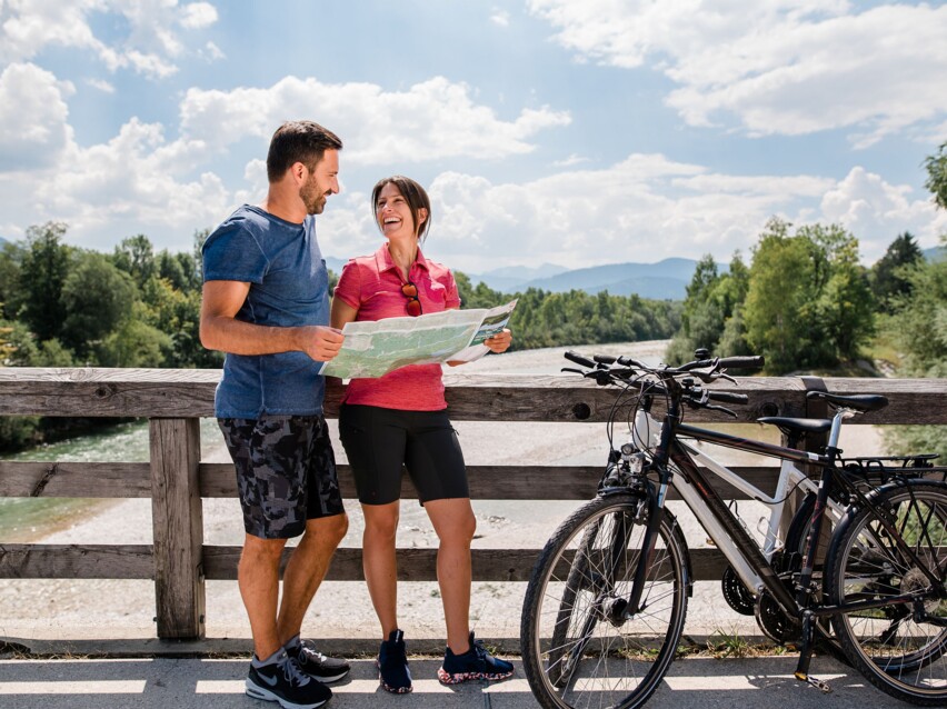Ein Paar schaut in eine Fahrrad-Karte auf einer Brücke über der Isar