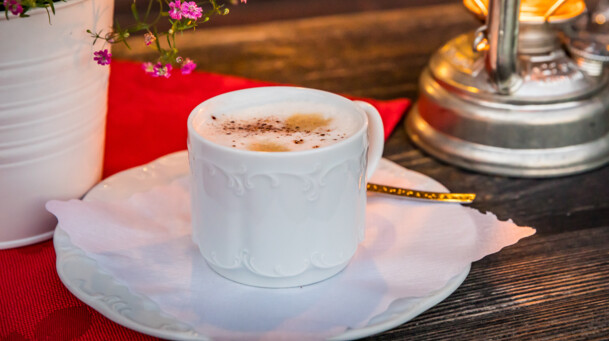 Tasse Cappuccino mit Blumen und Laterne