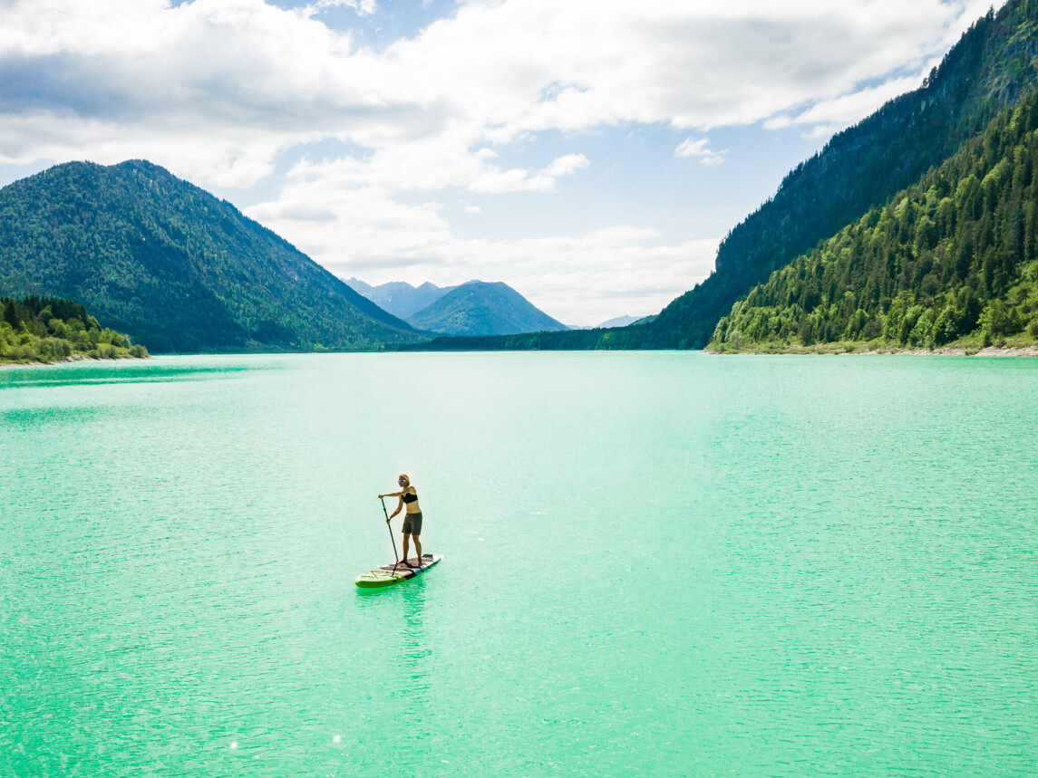 SUP Fahrerin im türkisfarbenen Wasser am Sylvensteinsee