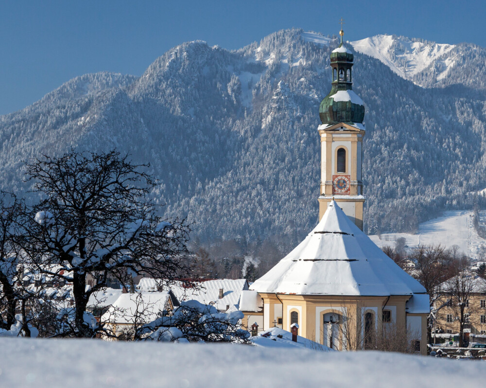 Ortsmitte Lenggries mit Pfarrkirche Sankt Jakob und Brauneck im Winter