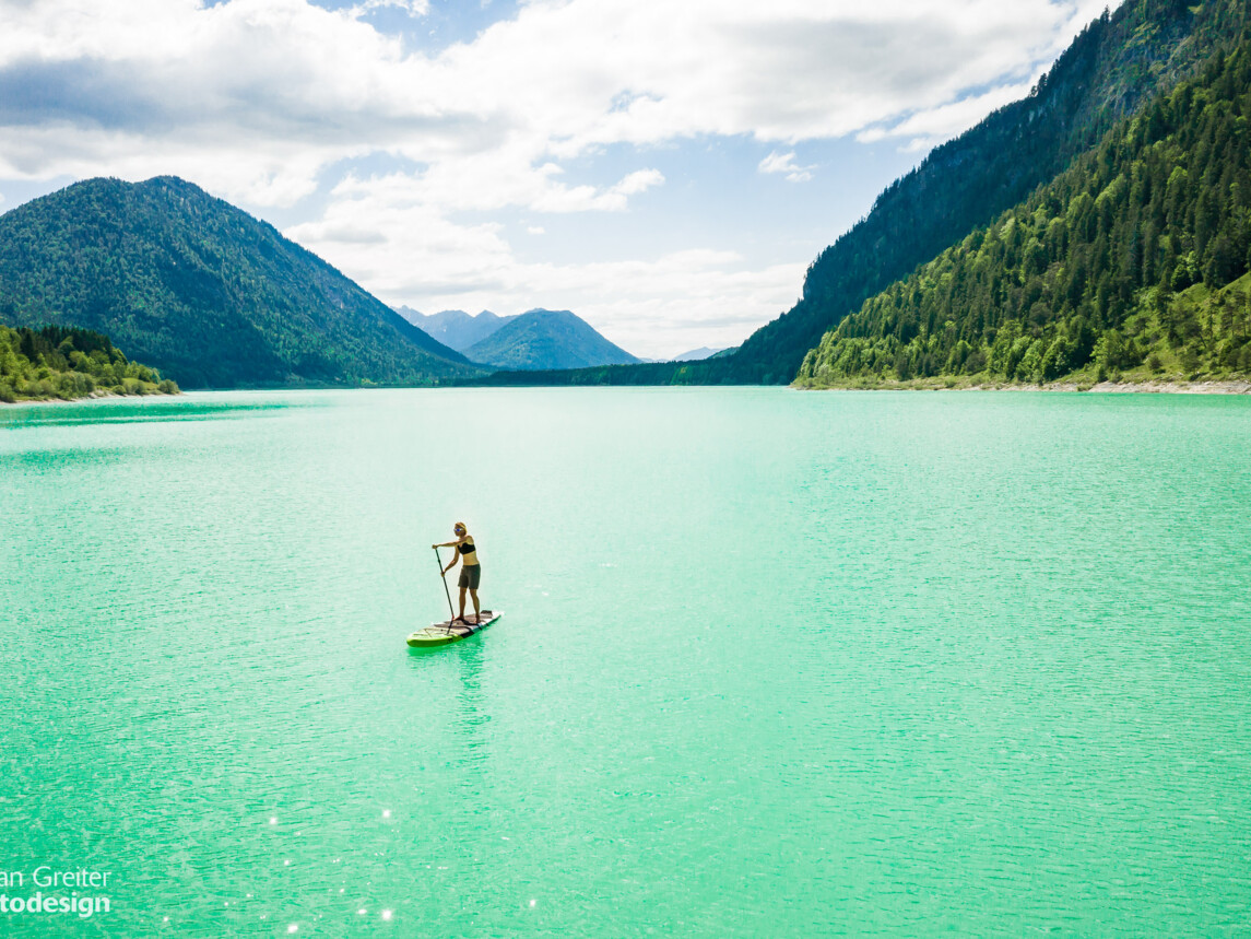 SUP Fahrerin im türkisfarbenen Wasser am Sylvensteinsee