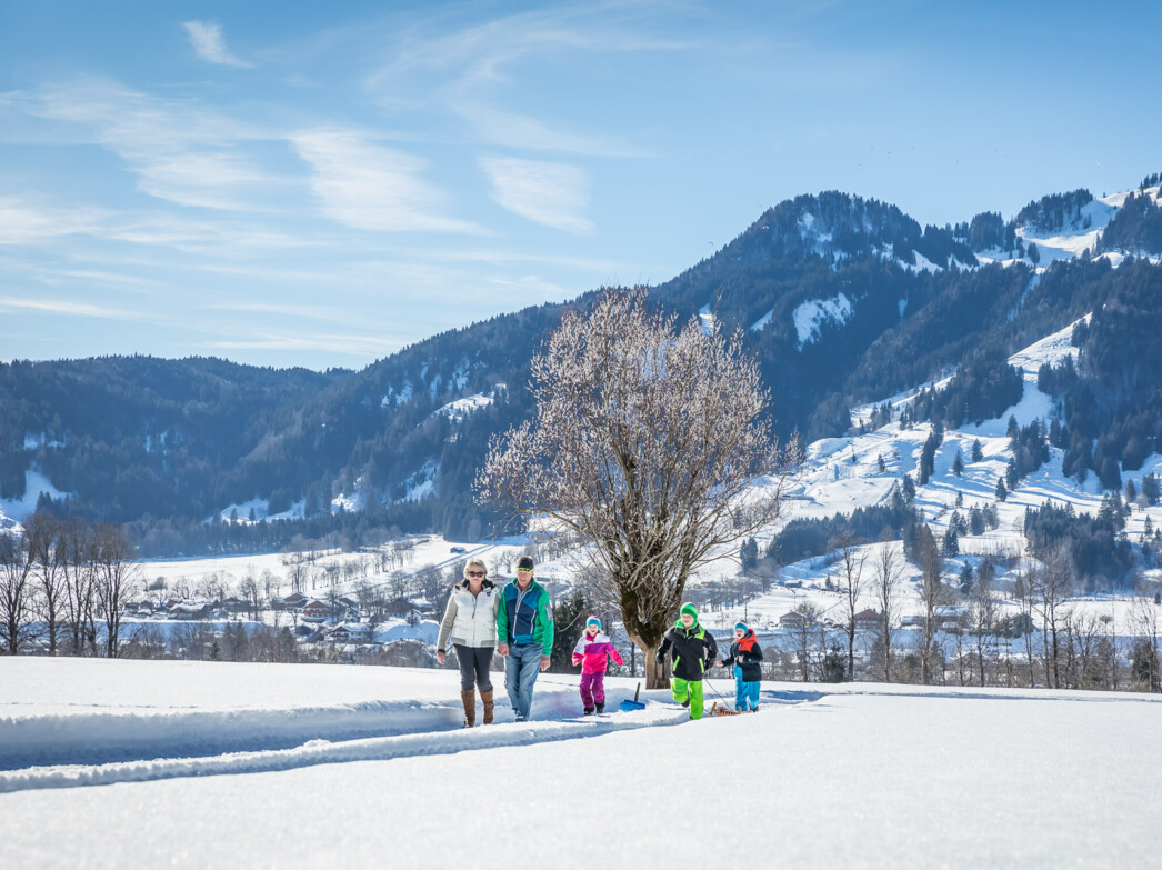 Familie beim Winterwandern mit Lenggries und Brauneck im Hintergrund