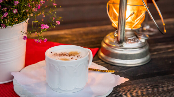 Tasse Cappuccino mit Blumen und Laterne
