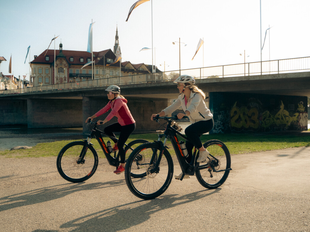 Zwei Frauen fahren mit dem Fahrrad unter der Isarbrücke Bad Tölz